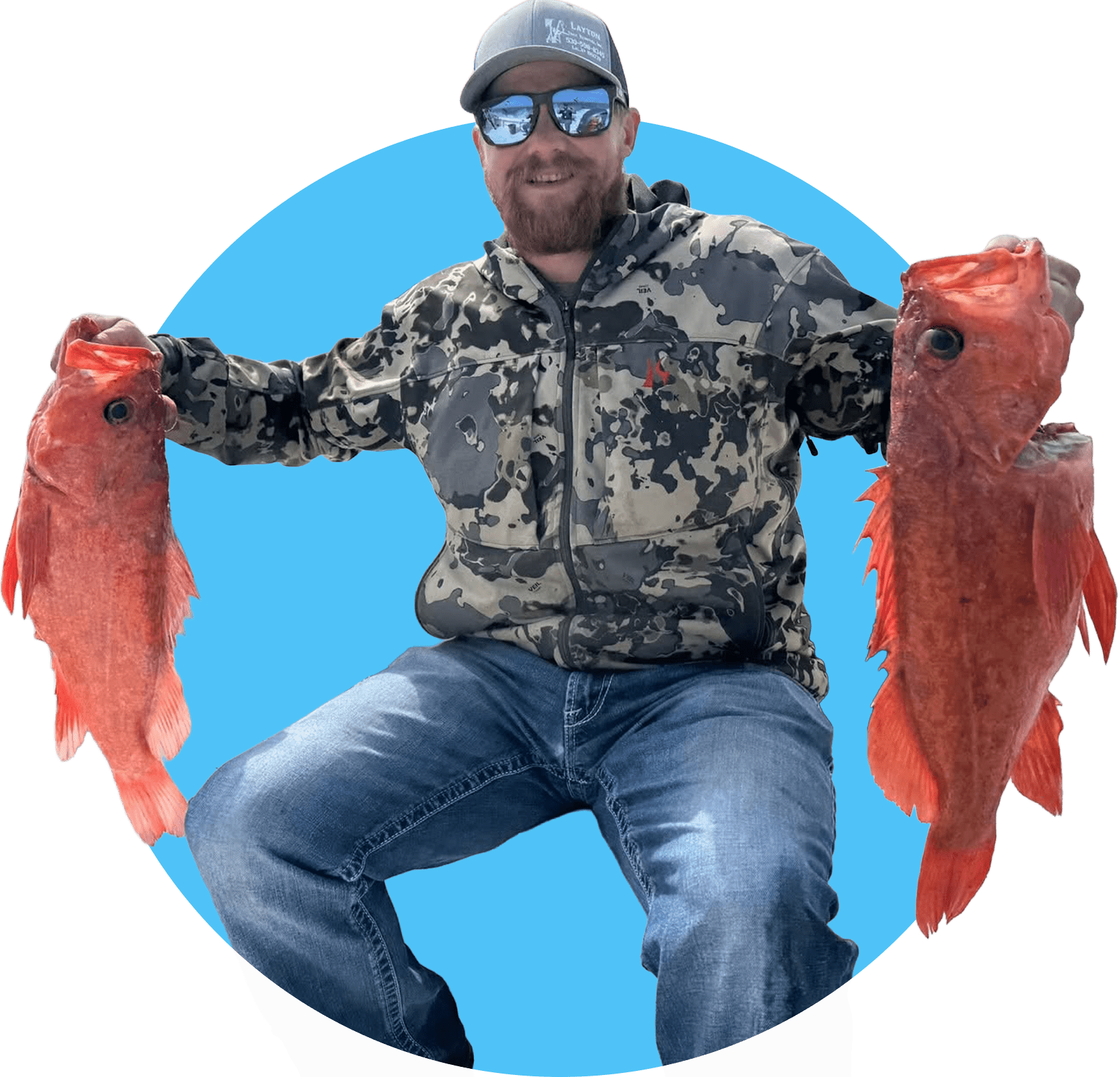 A smiling man in camouflage holds two large red fish, showcasing his successful catch while seated against a bright blue background.